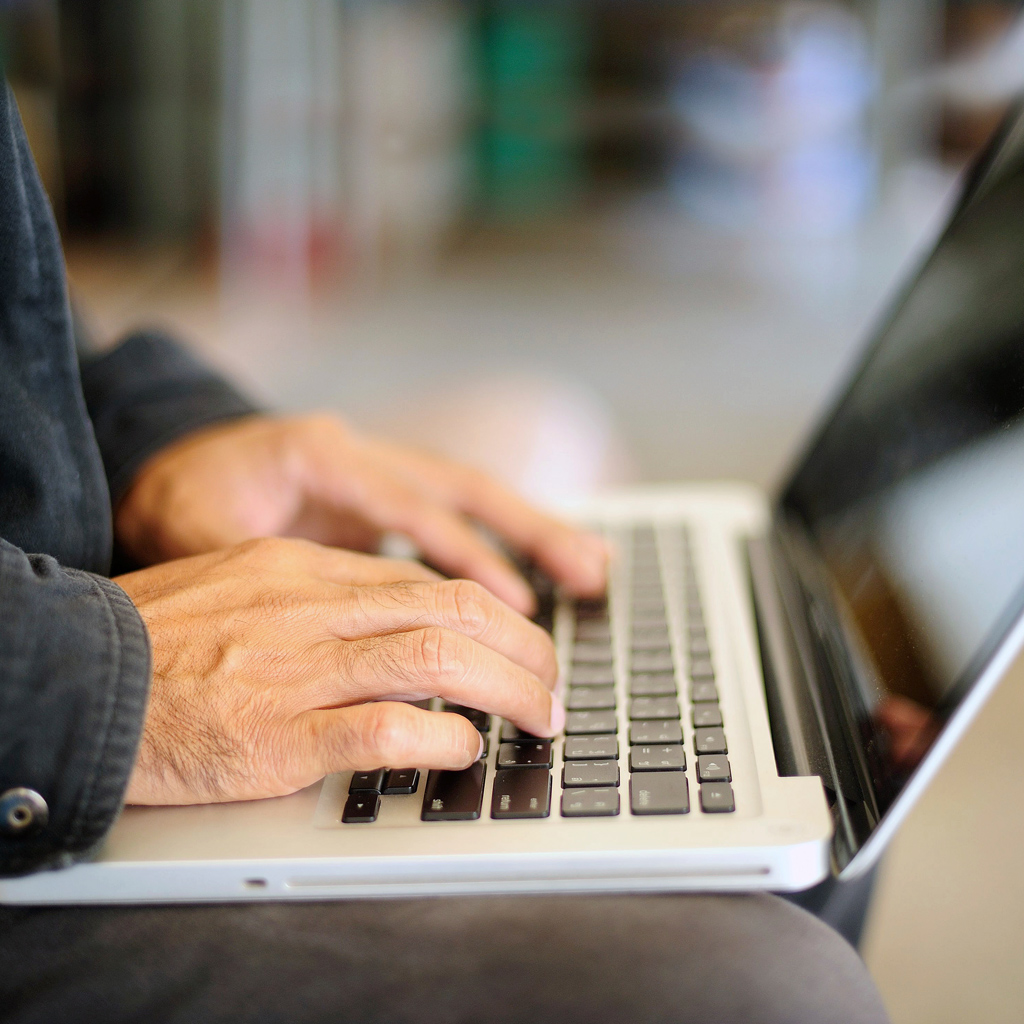 Close up of a man typing on a laptop.