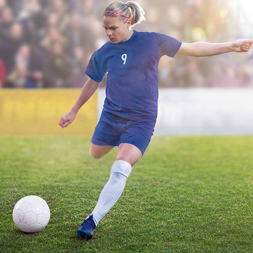 Eugenie Le Sommer kicking a football on the field. 