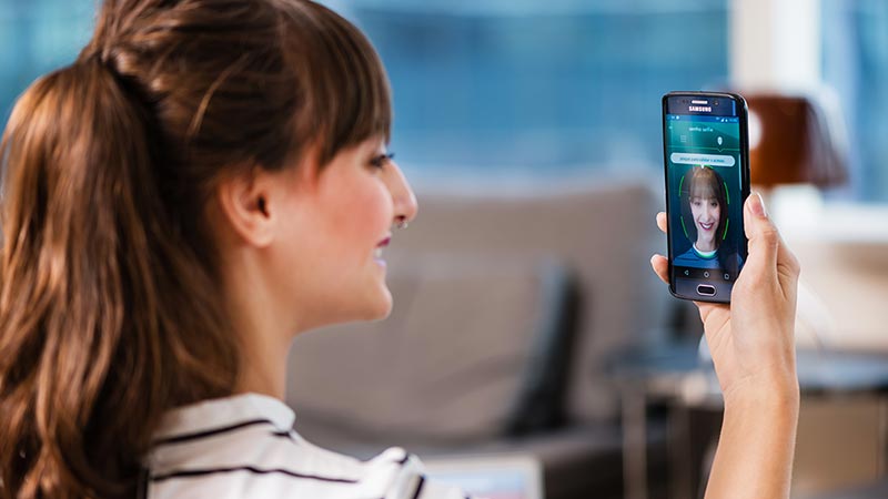 Woman using smart phone to calibrate facial recognition.