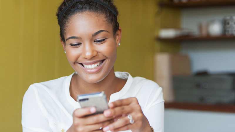 merchant-phone-800x450 A smiling woman looks at her phone.
